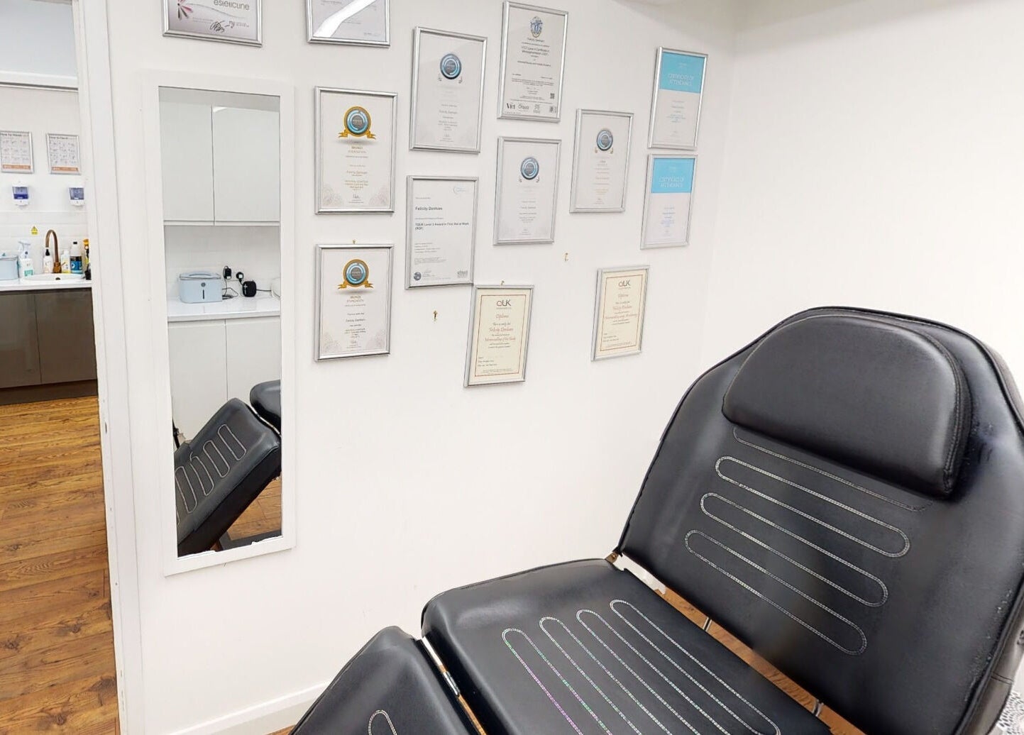 Professional certificates adorn the wall at The Avalon Rooms, Witney, England, GB, beside a sleek treatment chair.