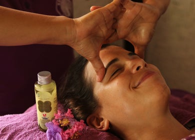 Relaxing face massage at Yogi Spa, Bali, Bali, ID with aromatic oils and flowers enhancing the peaceful ambiance.