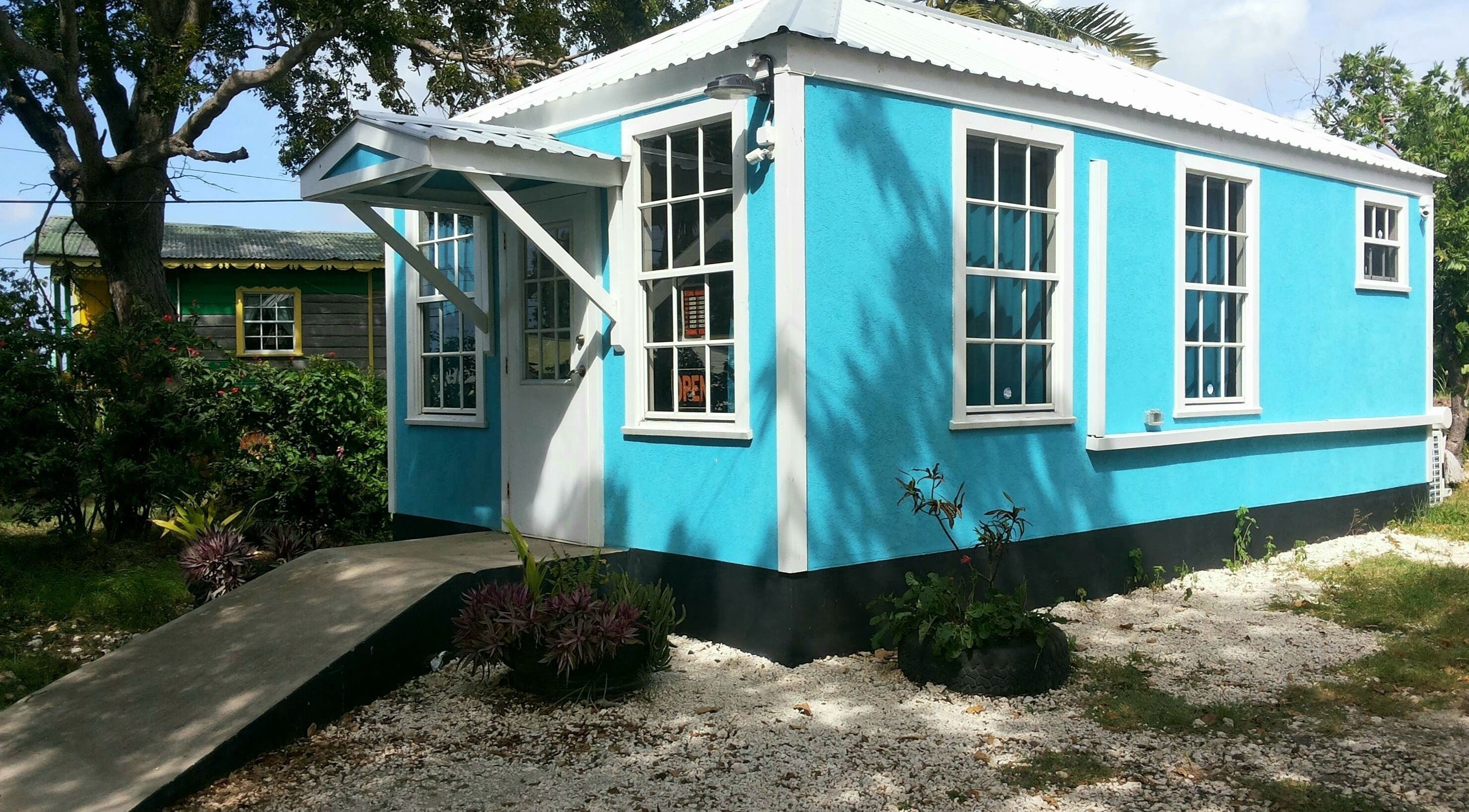 Bright blue exterior of The New Classic Barber Studio in Bridgetown, Saint Philip, BB, surrounded by greenery.