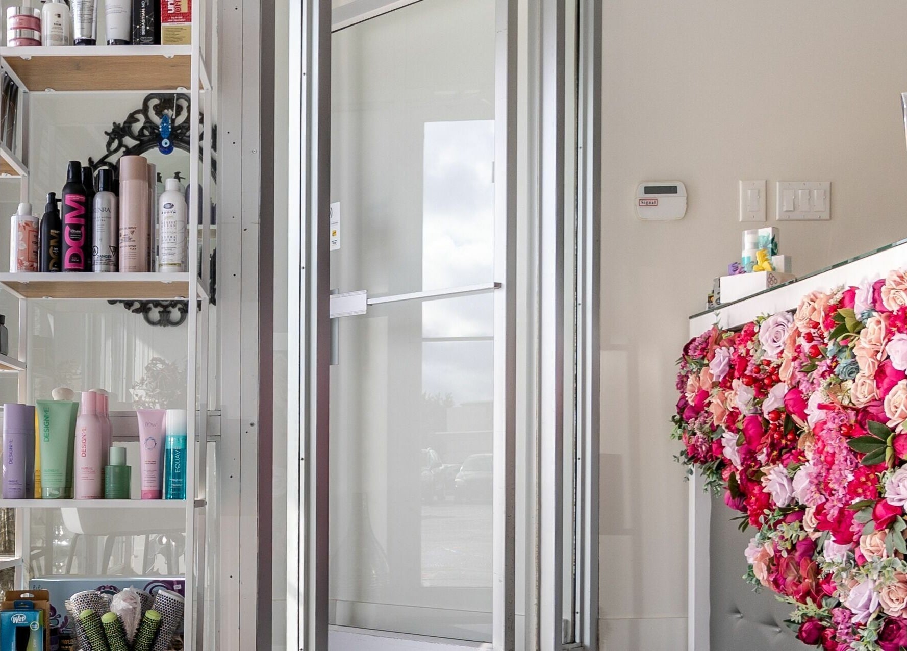Lolo's Salon entrance in Laval, Québec, CA, showcasing floral decor and hair products on stylish shelves.