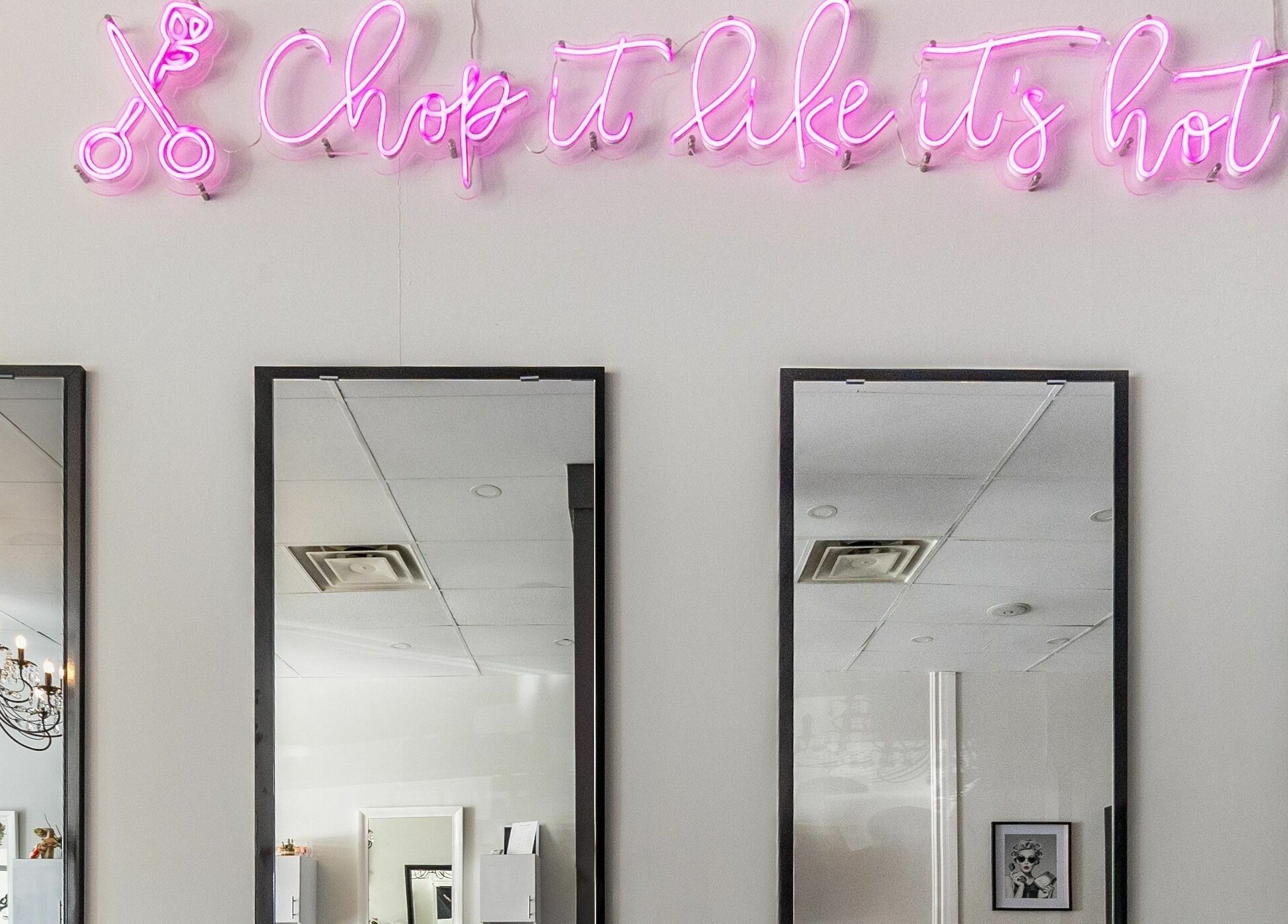 Lolo's Salon in Laval, Québec, CA features chic mirrors and a vibrant neon sign elevating the space.