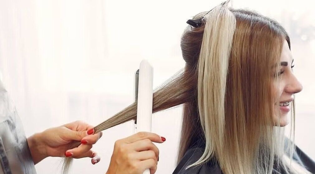 Stylist straightens hair at Passion Salon & Spa (Hill Avenue), Regina, Saskatchewan, CA.