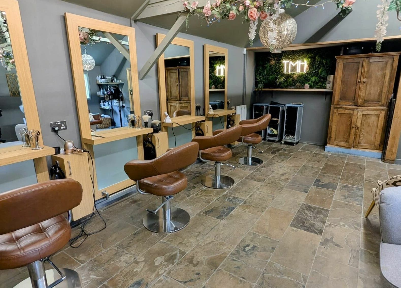 Elegant salon interior at The Mane House, Biddenden, England, GB with chic brown chairs and mirrors.