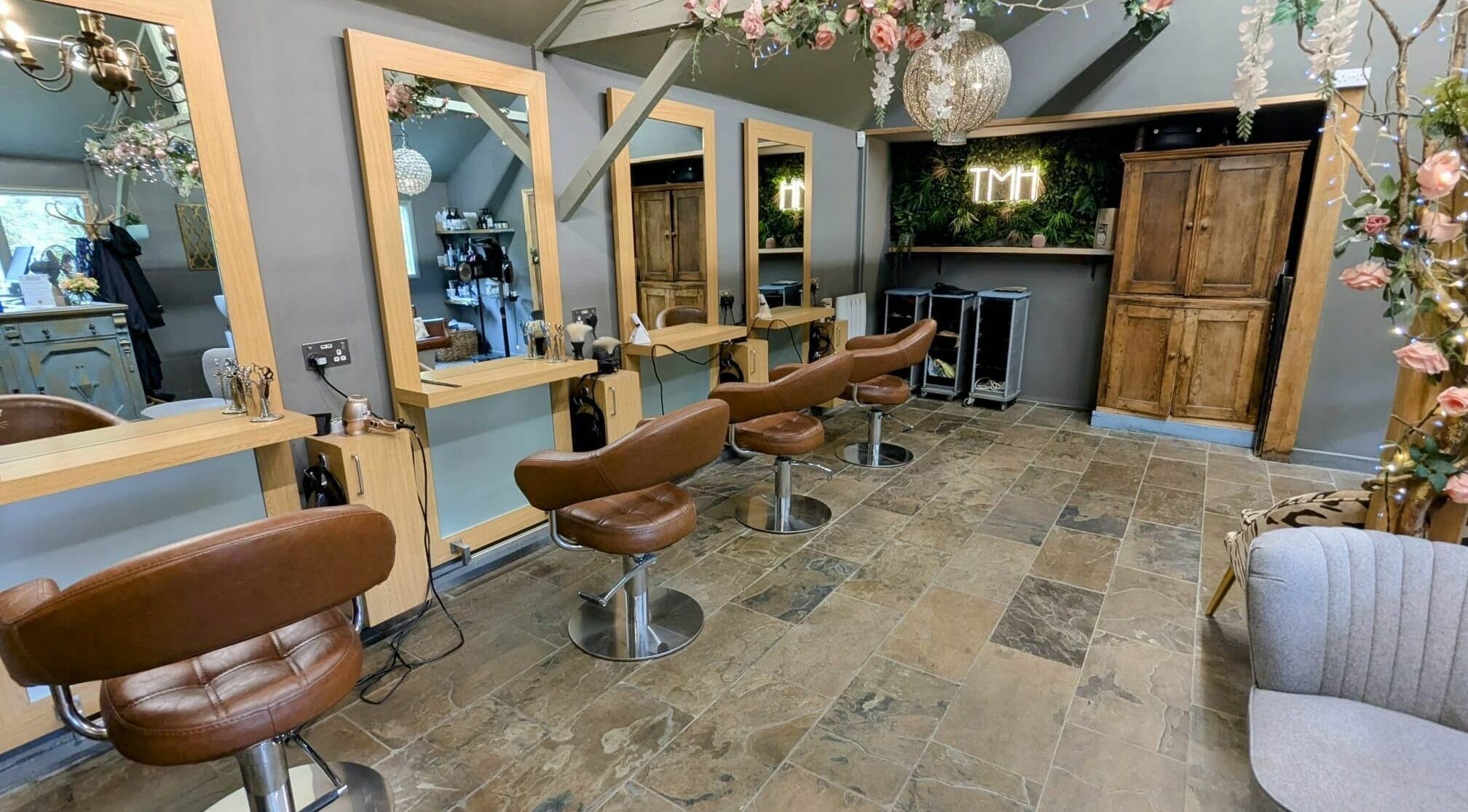 Elegant salon interior at The Mane House, Biddenden, England, GB with chic brown chairs and mirrors.