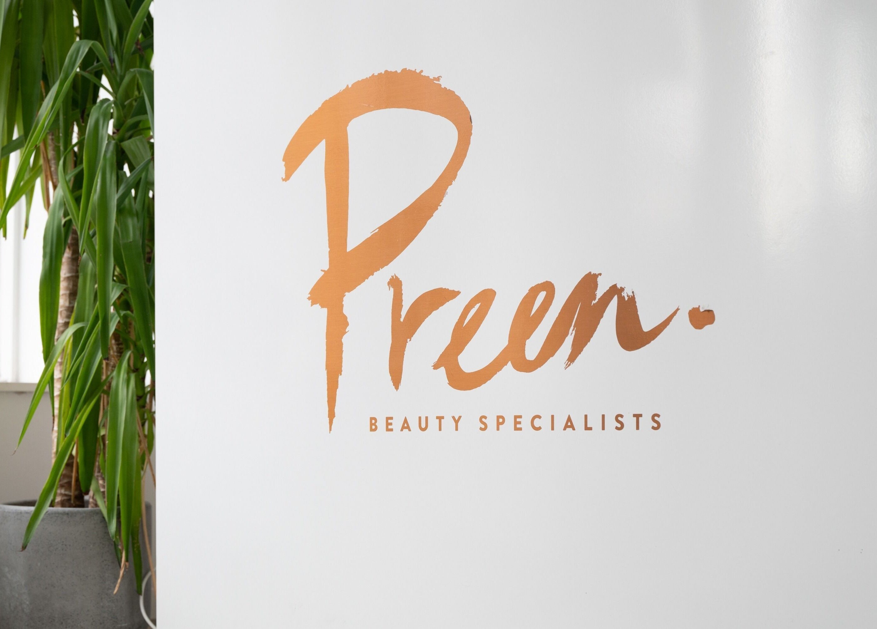 Preen Stockport entrance sign with green plant decor.