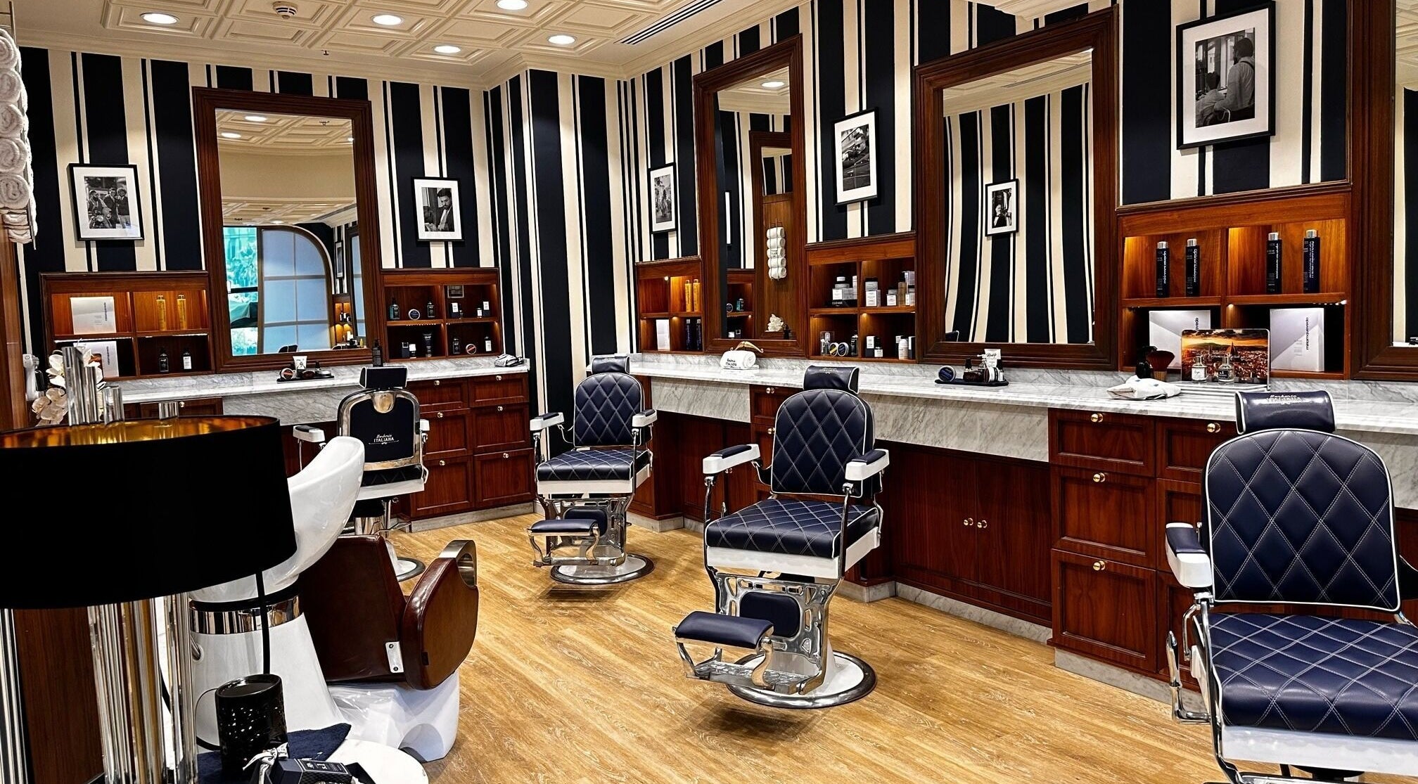 Interior of Barberia Italiana Grooming Lounge Ltd. in Dubai, Dubai, AE with luxurious barber chairs and wooden decor.