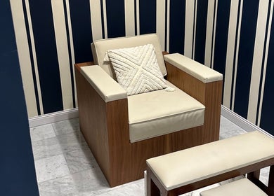 Elegant lounge chair at Barberia Italiana Grooming Lounge Ltd., Dubai, Dubai, AE with striped blue wallpaper.