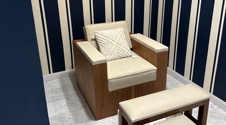 Elegant lounge chair at Barberia Italiana Grooming Lounge Ltd., Dubai, Dubai, AE with striped blue wallpaper.