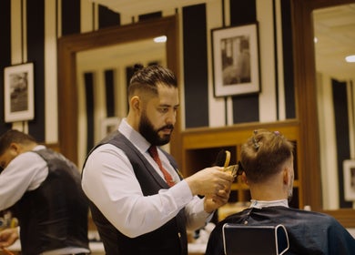 Skilled barber at Barberia Italiana Grooming Lounge Ltd. Dubai, Dubai, AE, provides a precise haircut.