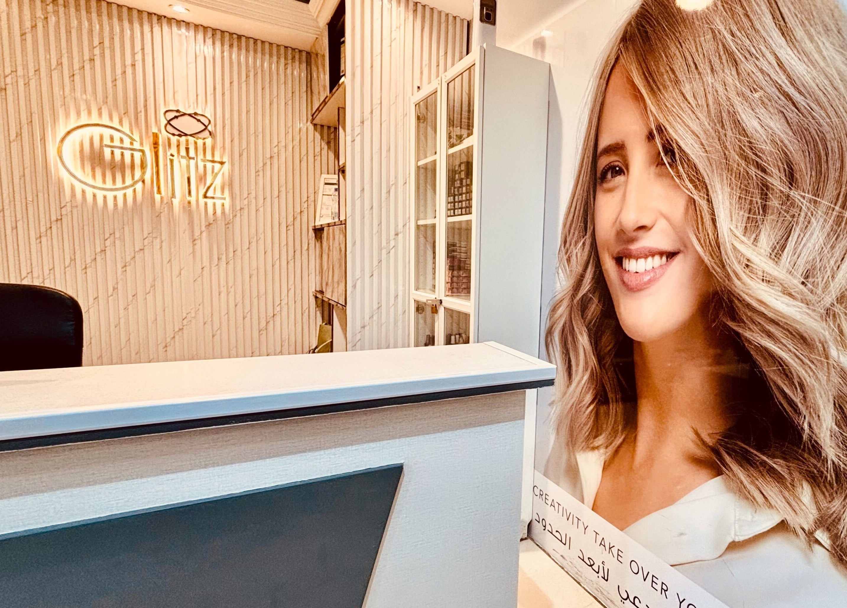 Welcoming reception area at Glitz Beauty Center, Dubai, AE with elegant decor and glowing signage.