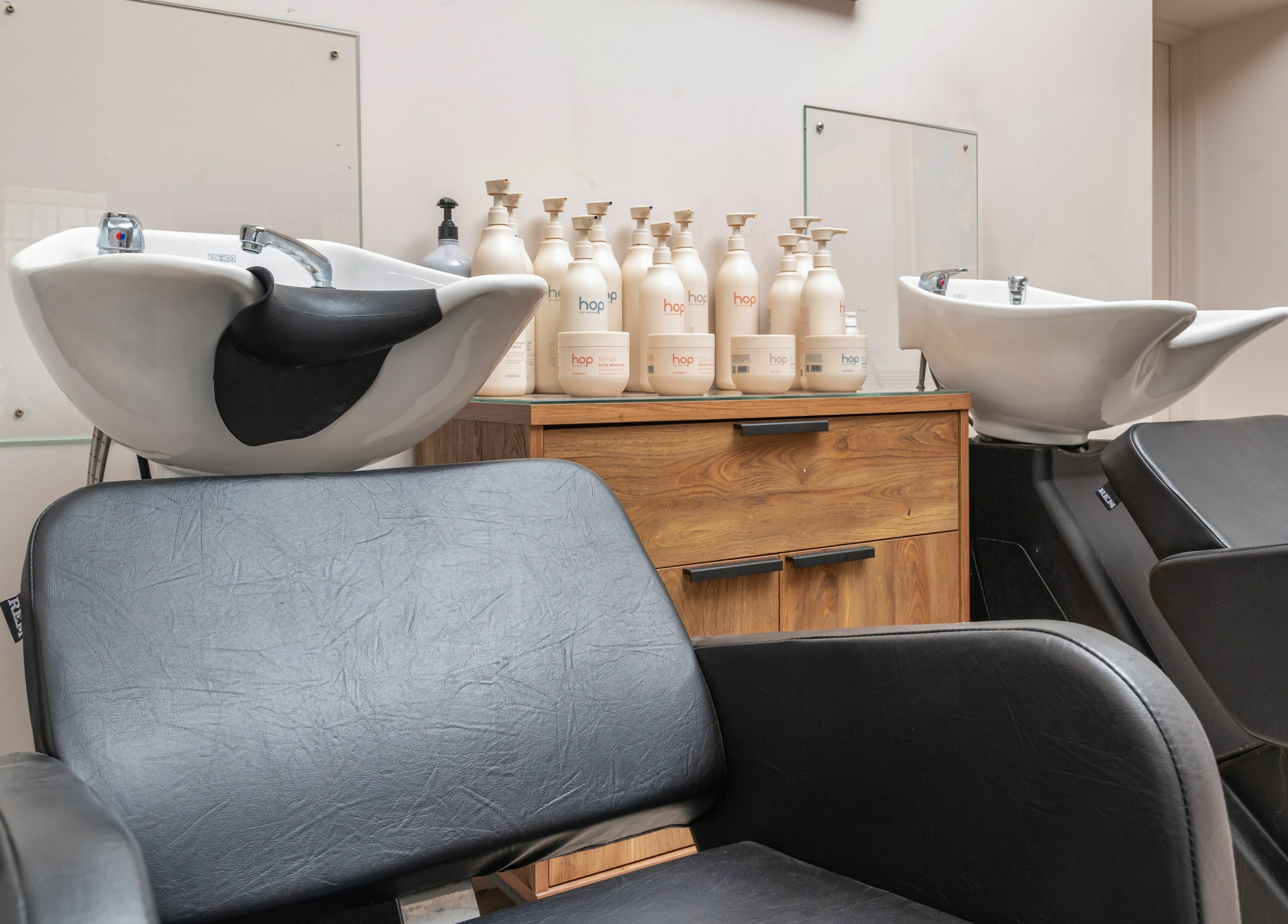 Modern hair salon station at Elcot Park Retreat, Newbury, England, GB, featuring chic black chairs and sink.