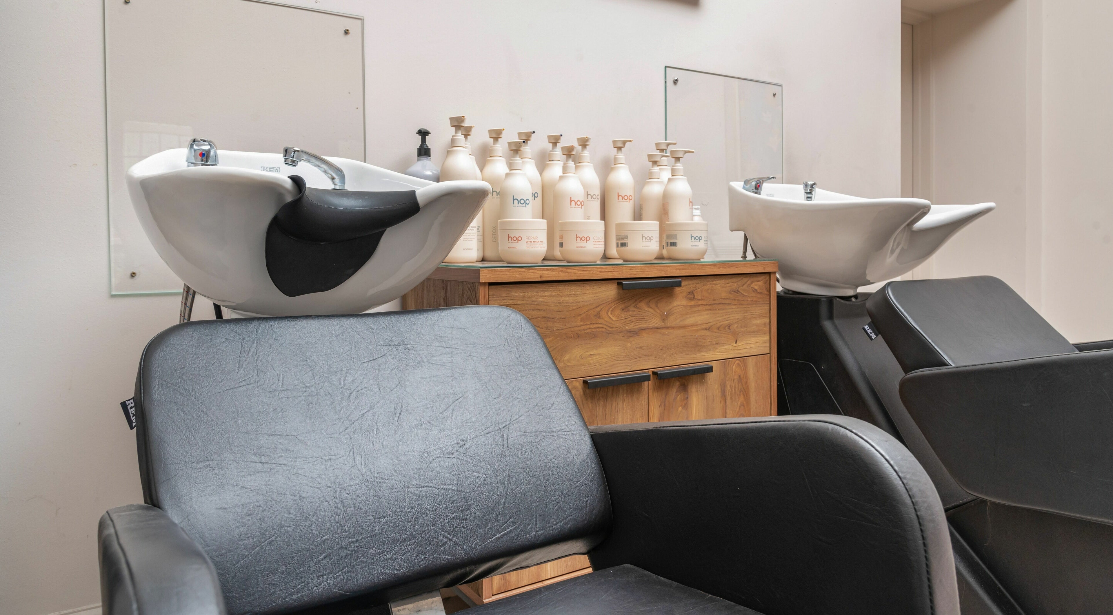Modern hair salon station at Elcot Park Retreat, Newbury, England, GB, featuring chic black chairs and sink.
