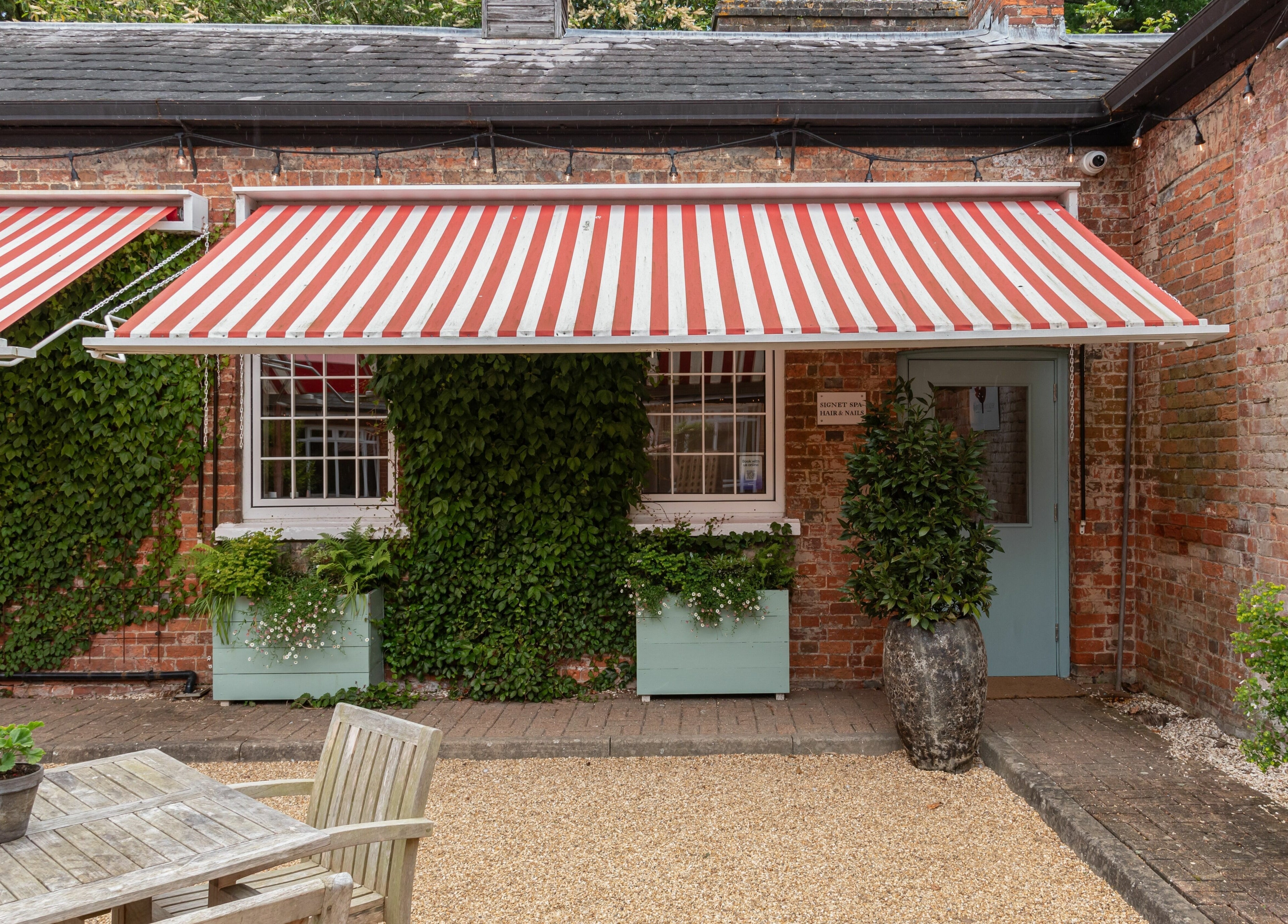 Elcot Park Retreat's ivy-adorned exterior with striped awnings in Newbury, England, GB.