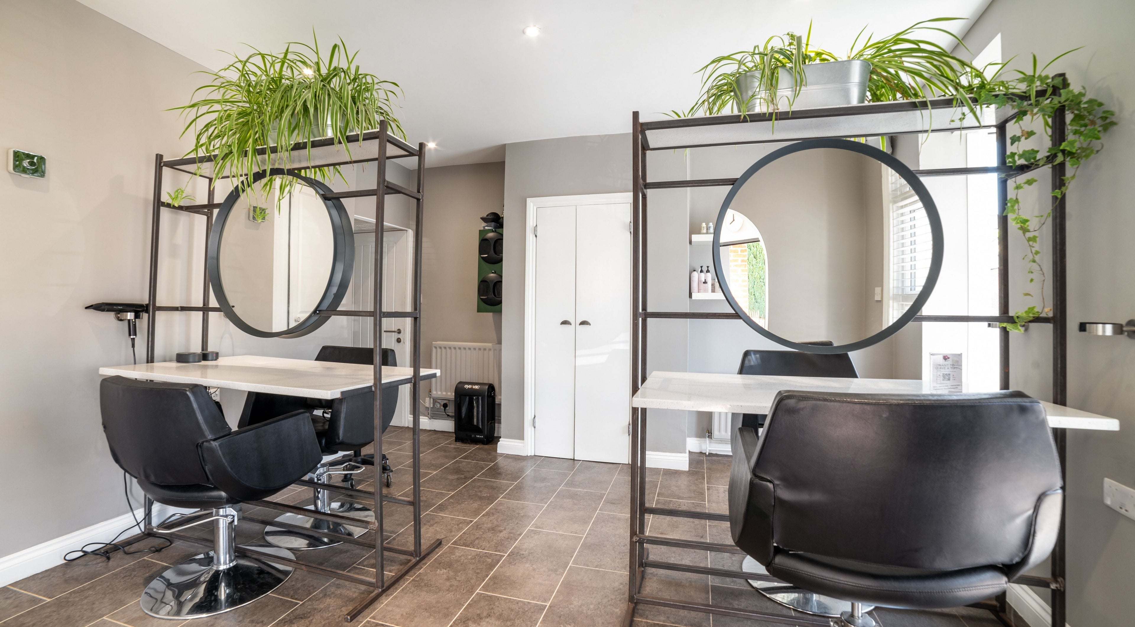 Modern styling stations at Sequoia Hair & Beauty in Newbury, England, GB, featuring chic black chairs and mirrors.