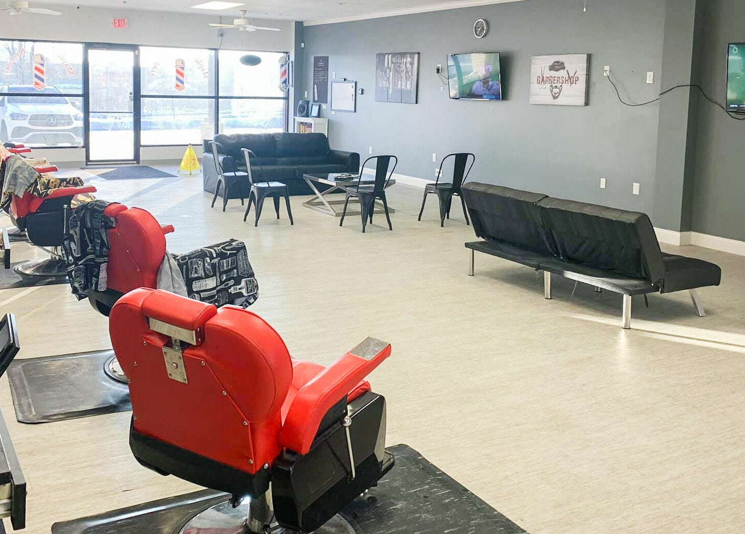Spacious interior of The Maple Barbers in Omaha, Nebraska, US featuring red chairs and modern decor.