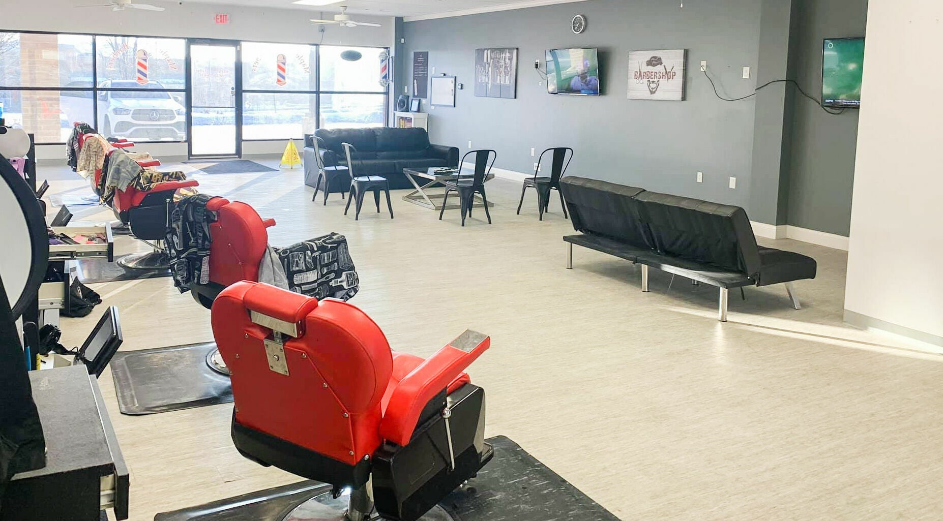 Spacious interior of The Maple Barbers in Omaha, Nebraska, US featuring red chairs and modern decor.