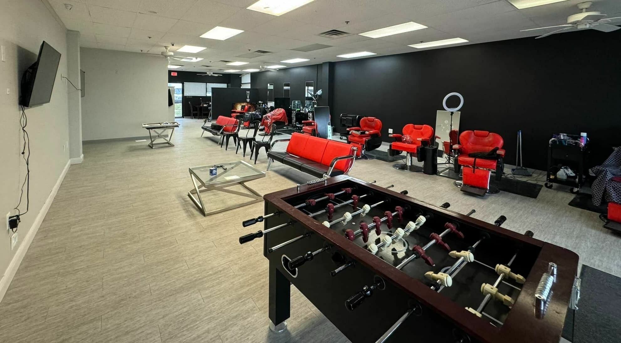 The Maple Barbers in Omaha, Nebraska, US with stylish red chairs and foosball table for a unique experience.