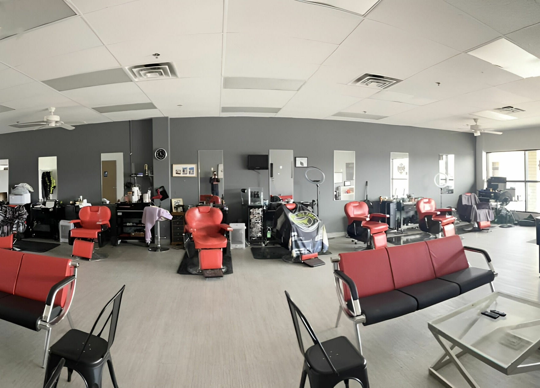 Spacious interior of The Maple Barbers in Omaha, Nebraska, US with red chairs and modern decor.
