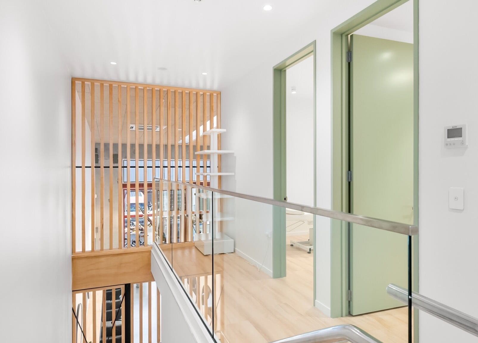 Bright, modern hallway at Beutiq, Wellington, Wellington, NZ with wooden accents and glass railing.