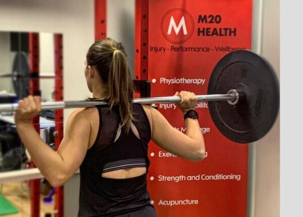 Woman lifting weights at M20 Health & Performance, Manchester, England, GB. Strength training session.