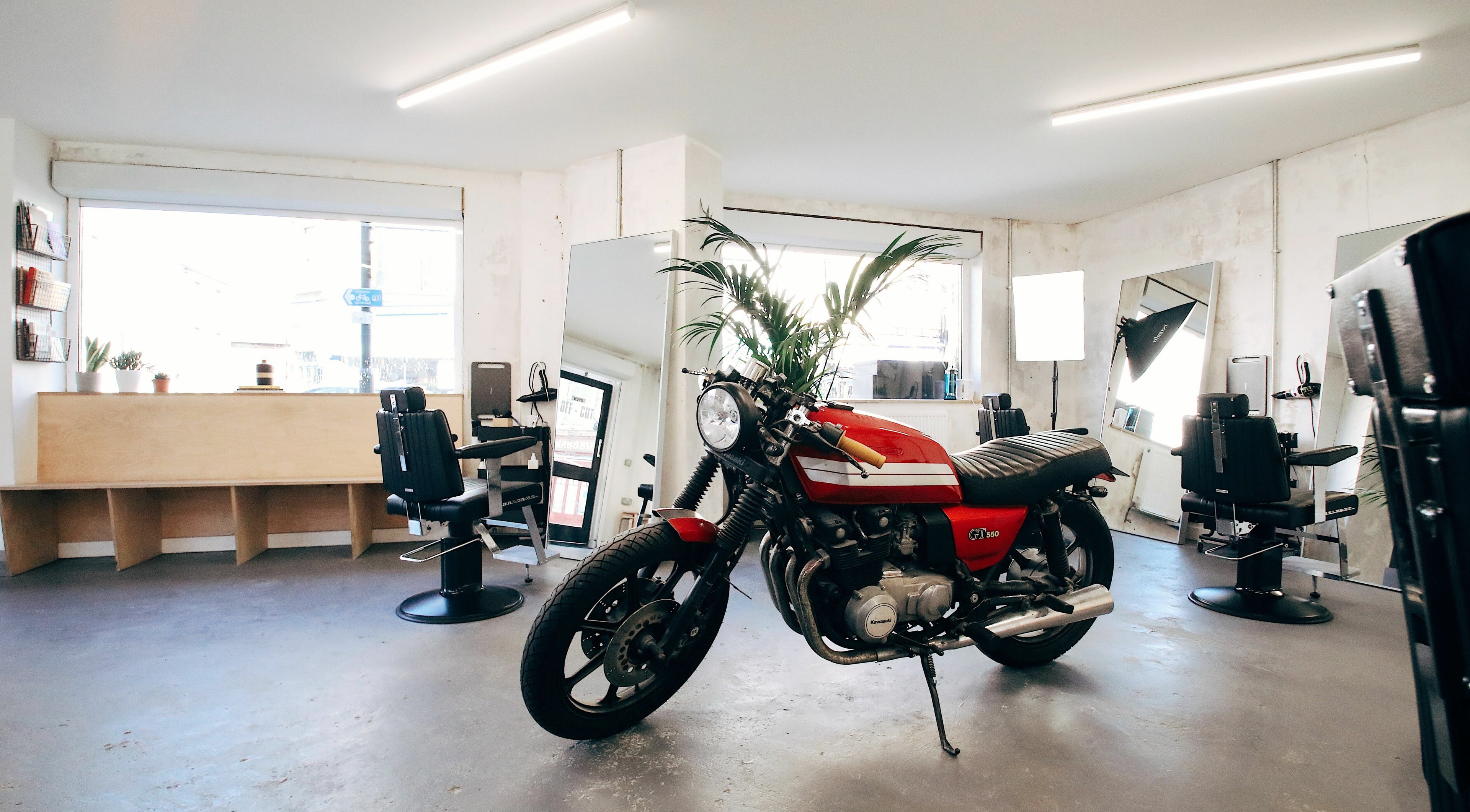 Modern salon interior at Off Cut, Camberwell, London, England, GB featuring a stylish motorcycle and sleek décor.
