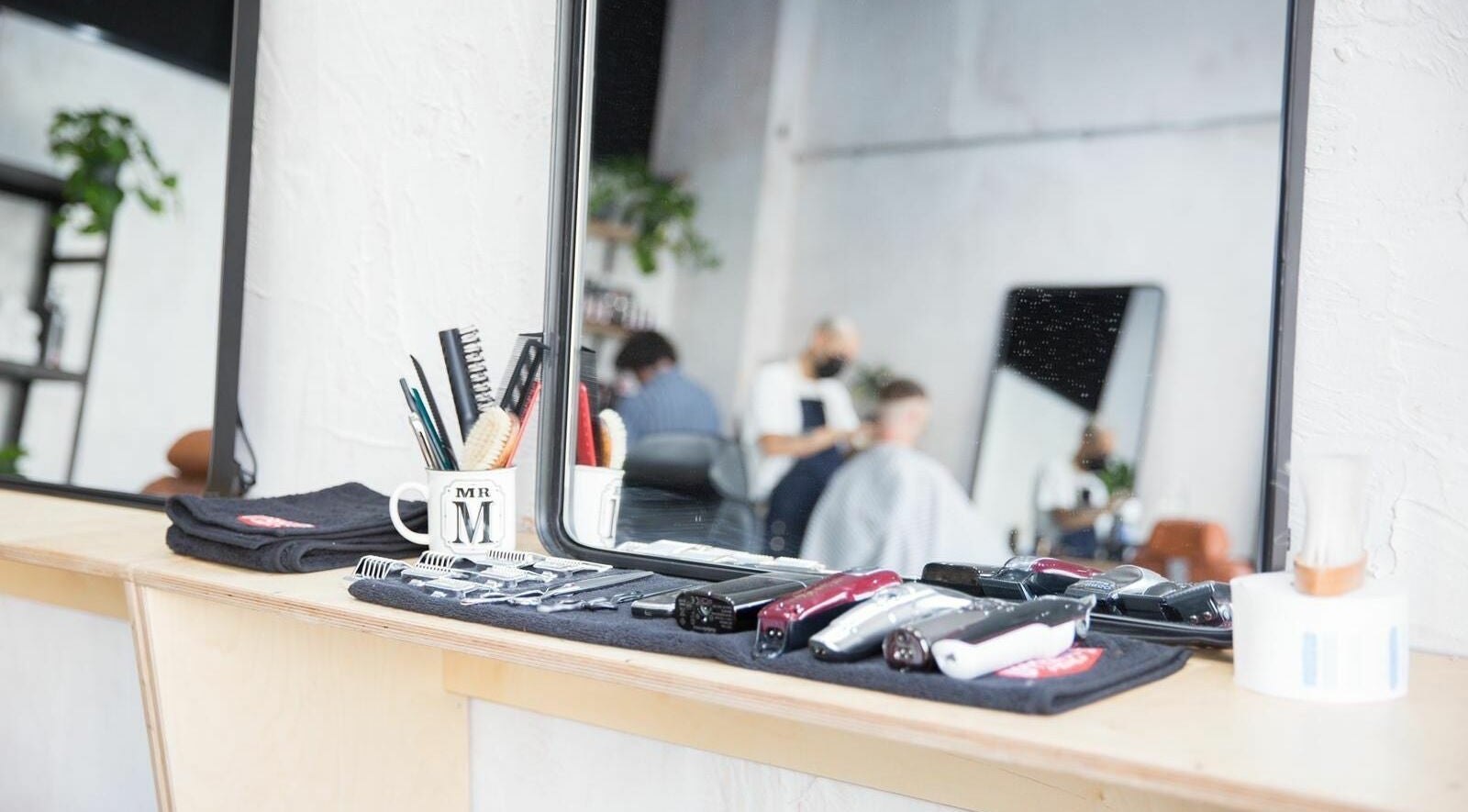 Hairdressing tools at Off Cut Streatham, London, England, GB with stylist working in background.
