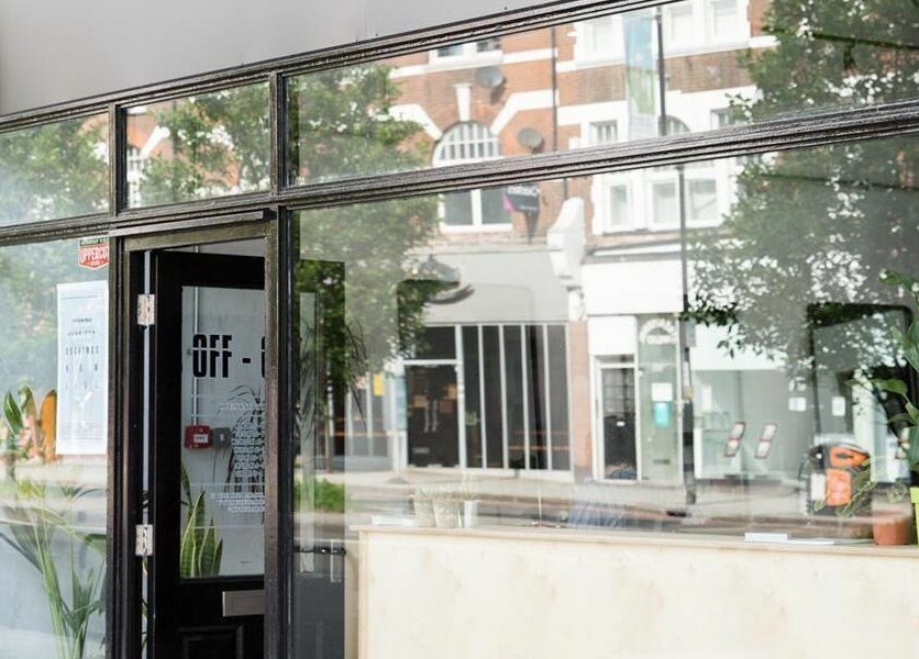 Street view of Off Cut Streatham entrance in London, England, GB with glass facade and plants.