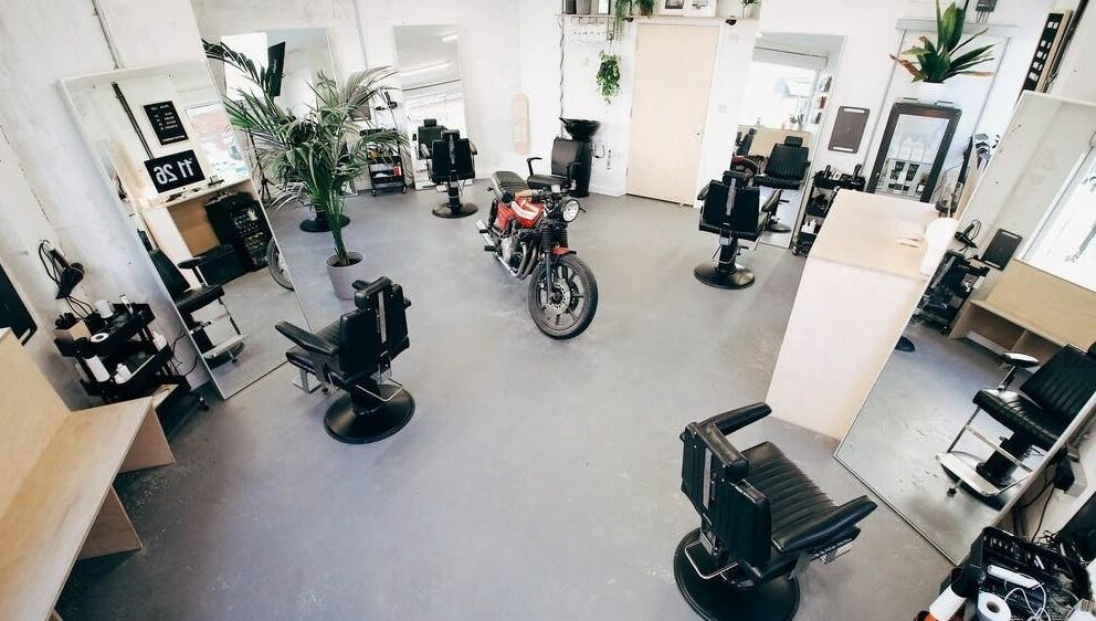 Stylish interior of Off Cut, Crystal Palace, London, England, GB, featuring sleek barber chairs and plants.