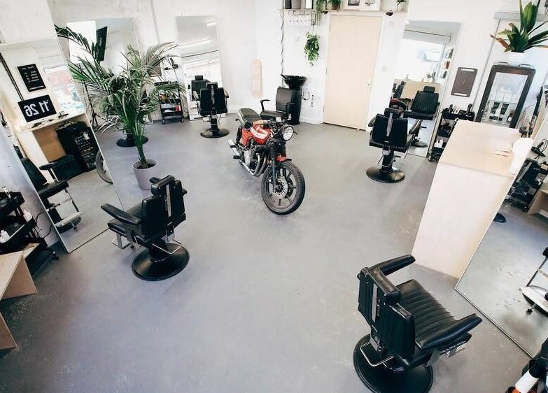 Stylish interior of Off Cut, Crystal Palace, London, England, GB, featuring sleek barber chairs and plants.