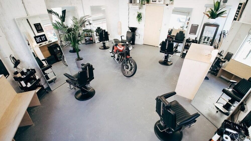 Stylish interior of Off Cut, Crystal Palace, London, England, GB, featuring sleek barber chairs and plants.