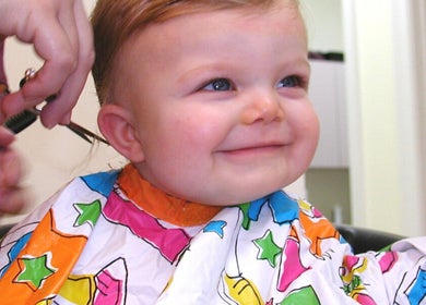 Cheerful child receiving a haircut at The Kids Hair Studio, Ryde, GB.