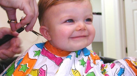 Cheerful child receiving a haircut at The Kids Hair Studio, Ryde, GB.