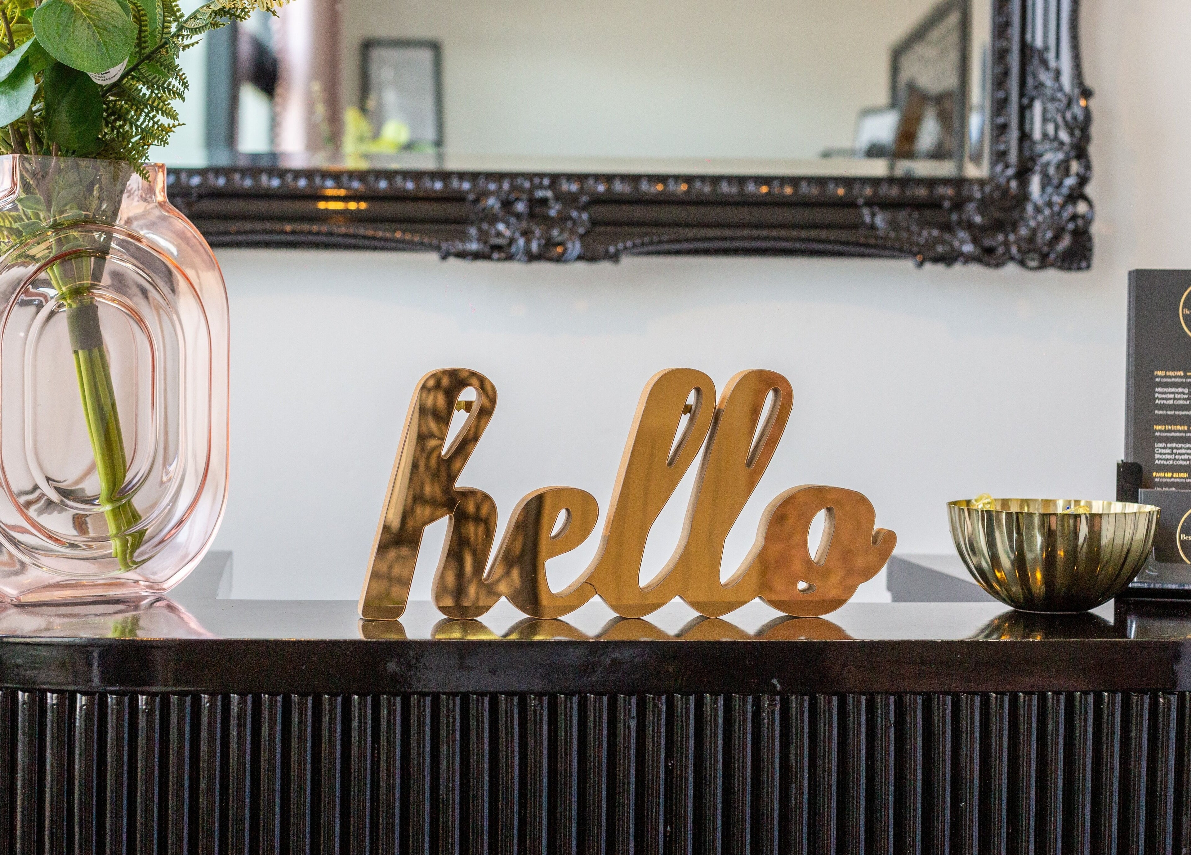 Reception desk at Bespoke Brow Design in Rustington, England, GB with vase, hello sign, and brochure display.