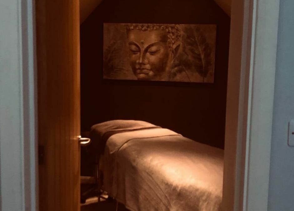 A cozy massage room at Pure Indulgence Day Spa in Merton, England, GB with serene Buddha art.