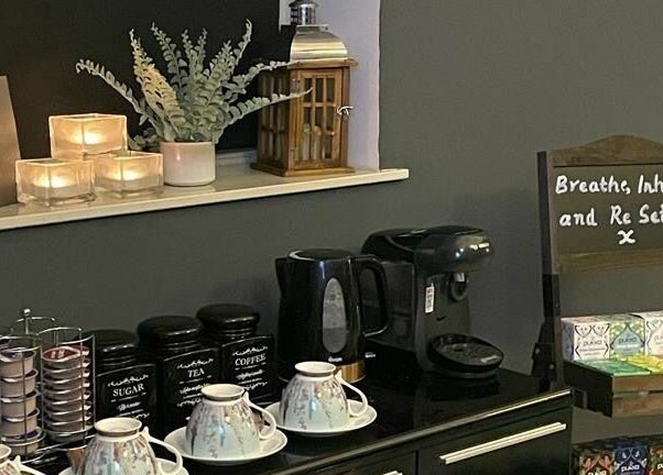 Relaxing tea and coffee corner at Pure Indulgence Day Spa, Merton, England, GB, with candles and soothing decor.
