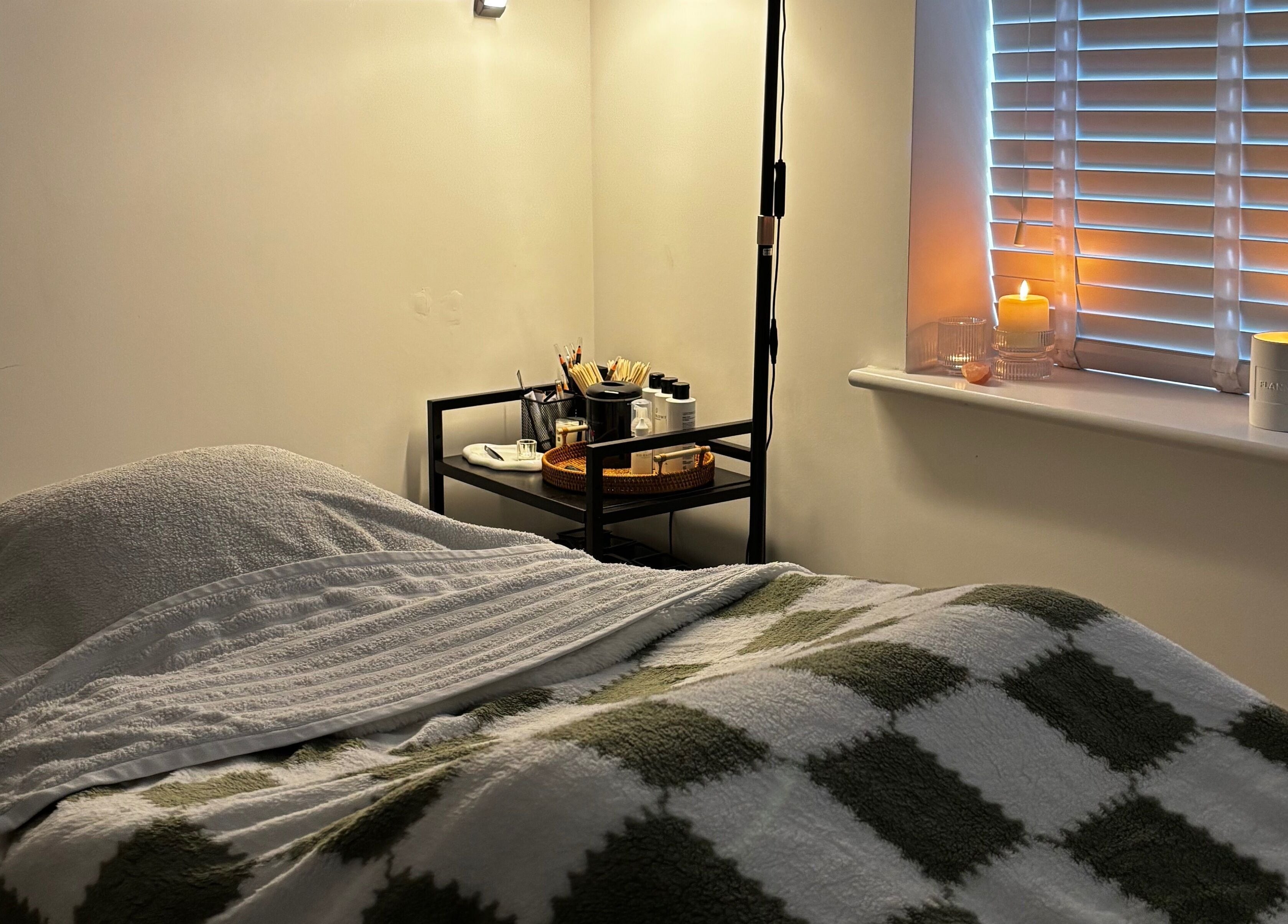 Relaxing treatment room at Sunday Rose, Shadoxhurst, England, GB with cozy bed and ambient candles.