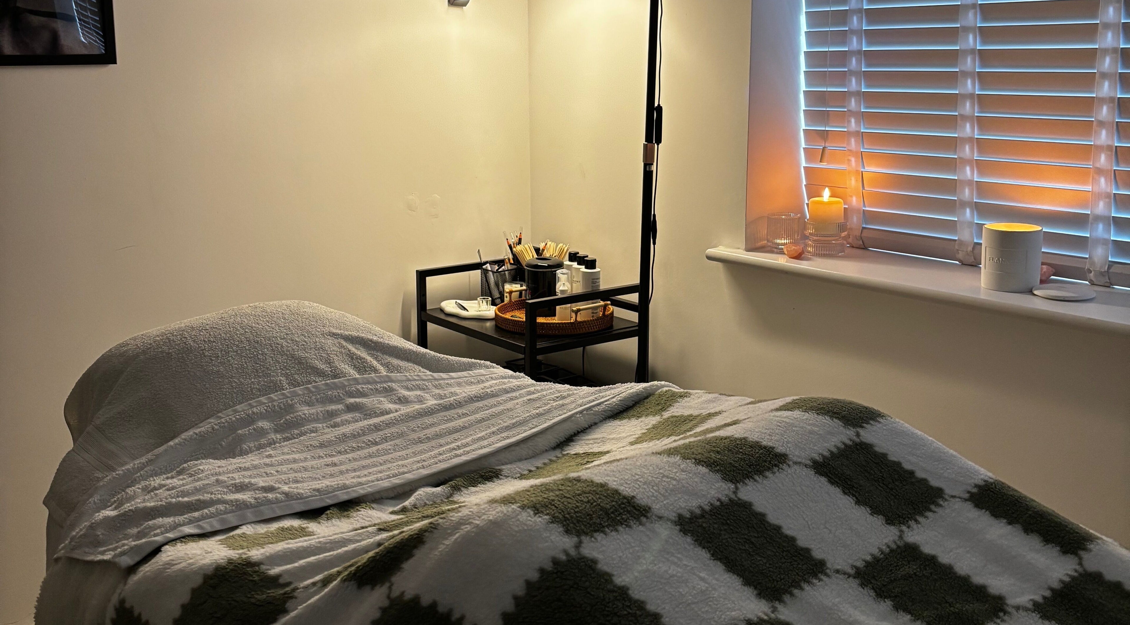 Relaxing treatment room at Sunday Rose, Shadoxhurst, England, GB with cozy bed and ambient candles.