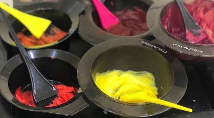 Bright hair dye bowls at Headquarters Salon in Reading, England, GB, showcasing vibrant color options.