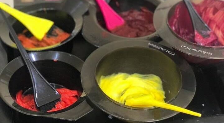 Bright hair dye bowls at Headquarters Salon in Reading, England, GB, showcasing vibrant color options.