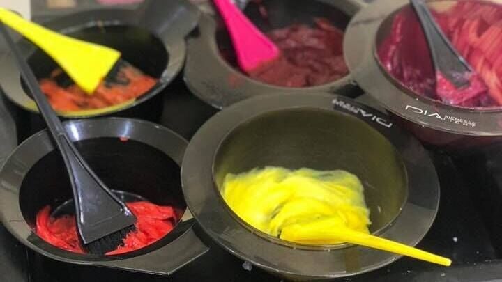 Bright hair dye bowls at Headquarters Salon in Reading, England, GB, showcasing vibrant color options.