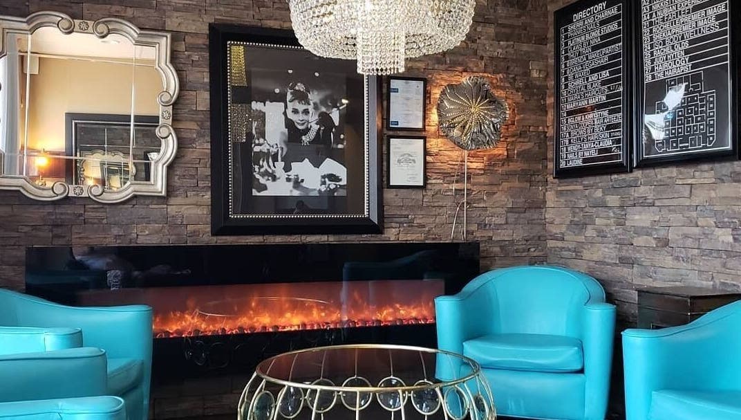 Chic lounge area at Charity's Essentials Ageless Spa, Yuma, ARIZONA, US. Features turquoise chairs and a cozy fireplace.