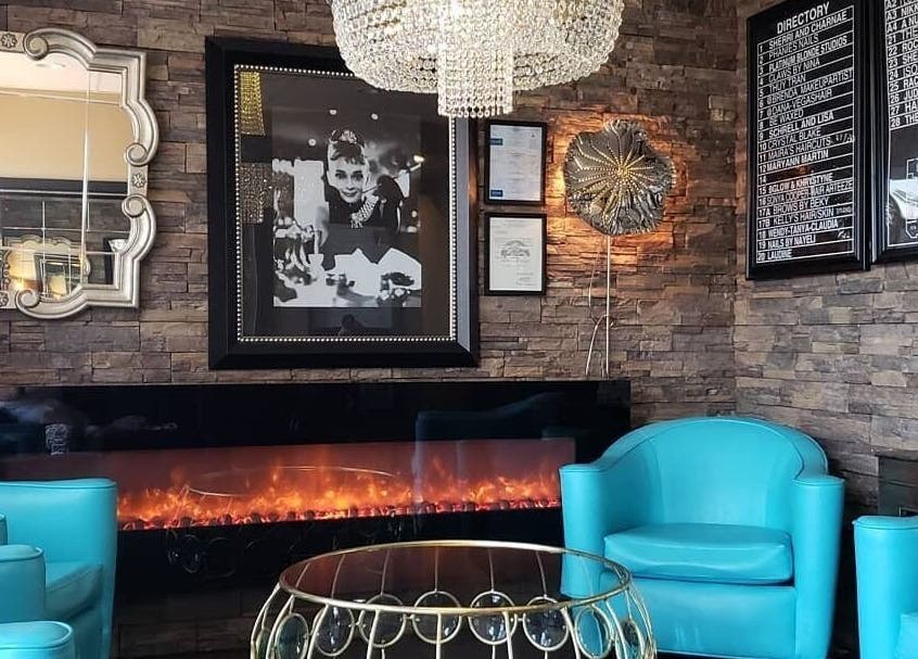 Chic lounge area at Charity's Essentials Ageless Spa, Yuma, ARIZONA, US. Features turquoise chairs and a cozy fireplace.