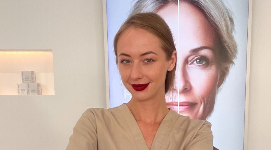 Professional at Skin Aesthetic in Trowbridge, England, GB, standing confidently in front of a beauty poster.