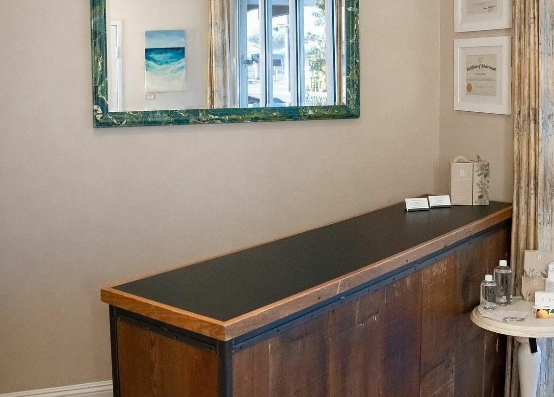 Reception desk at Sugar Maui, Kihei, Hawaii, US with decor and a large mirror reflecting natural light.
