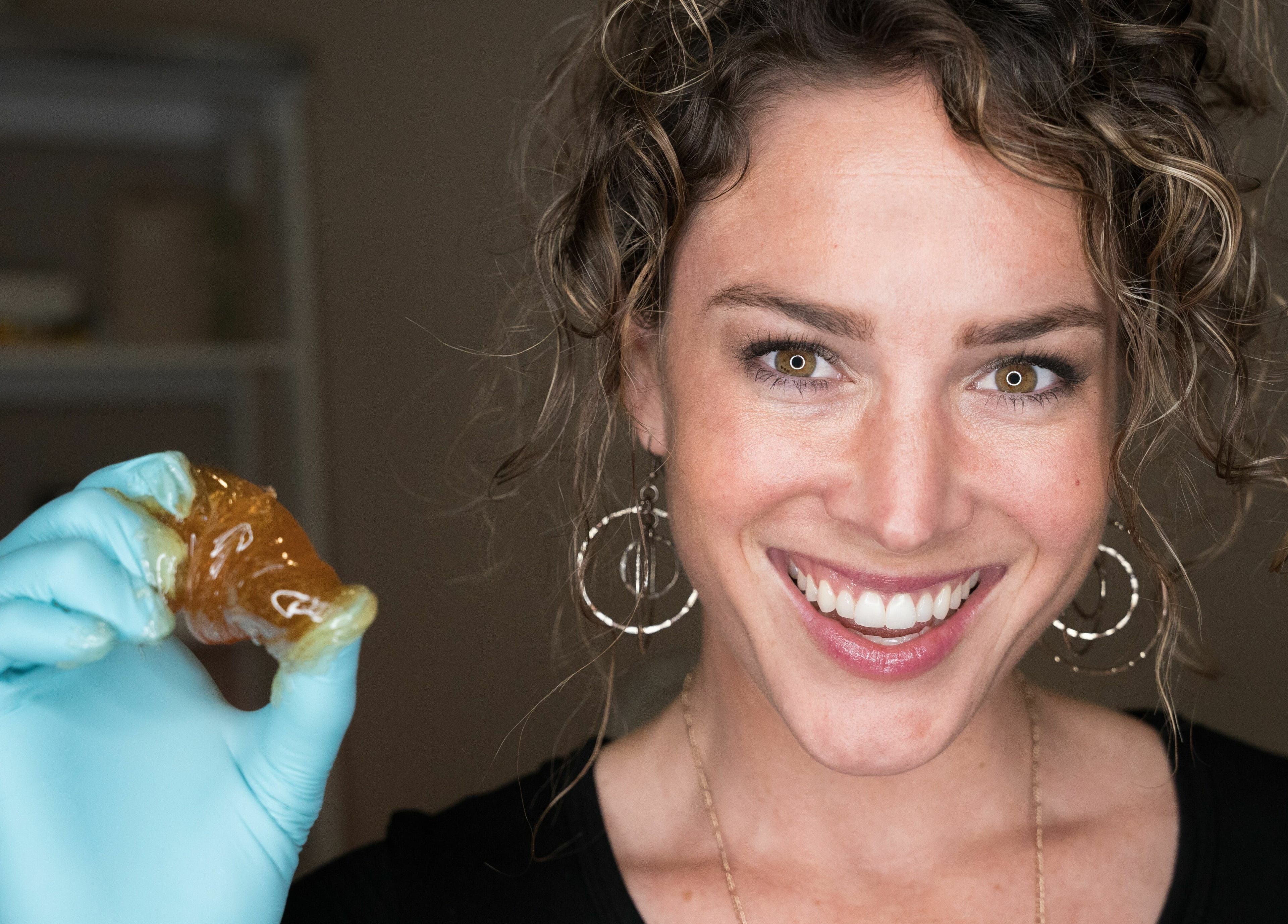 Smiling staff at Sugar Maui holds sugaring paste, emphasizing natural beauty in Kihei, Hawaii, US.