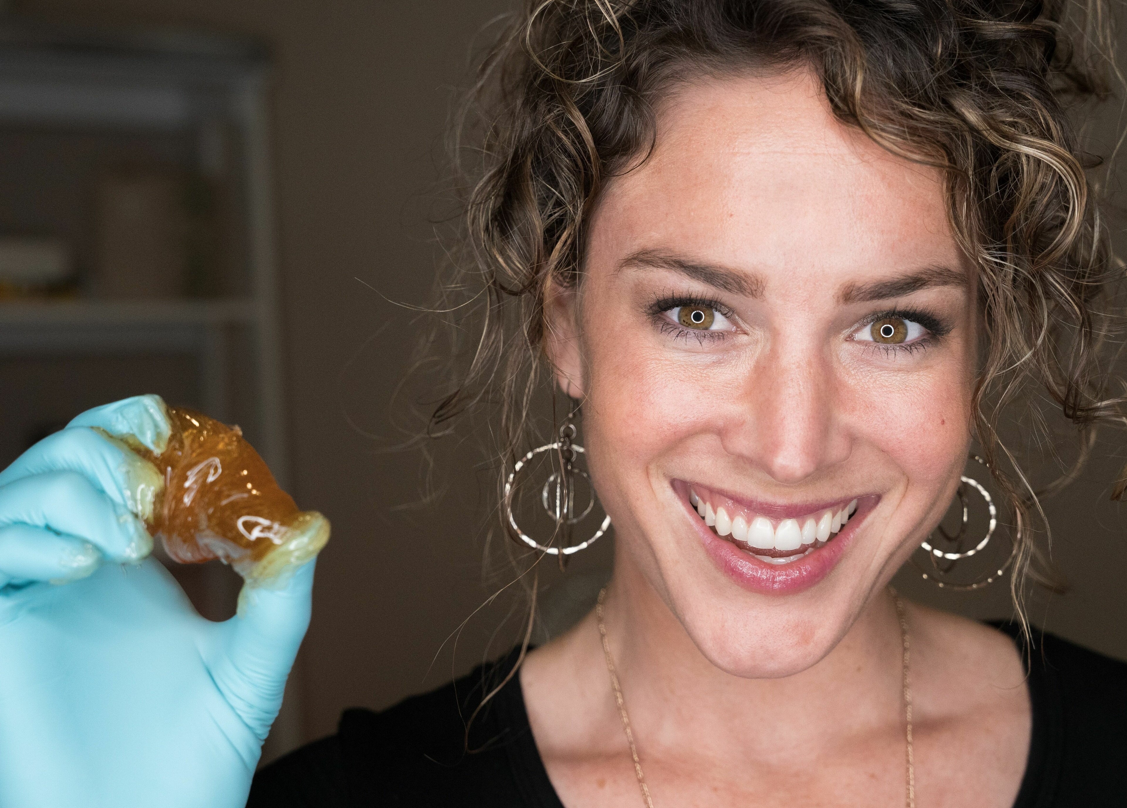 Smiling staff at Sugar Maui holds sugaring paste, emphasizing natural beauty in Kihei, Hawaii, US.