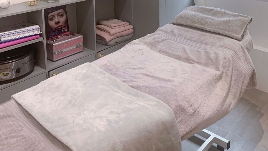 Cozy treatment bed in Nailsquad, Deal, England, GB with soft pink towels and elegant storage.