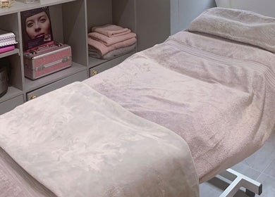 Cozy treatment bed in Nailsquad, Deal, England, GB with soft pink towels and elegant storage.