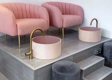 Luxurious pedicure chairs at Nailsquad, Deal, England, GB, with plush pink seating and elegant washbasins.