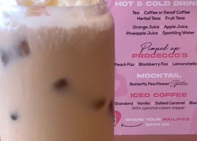 Chilled iced coffee with cream topper at Nailsquad, Deal, England, GB, alongside vibrant drinks menu.